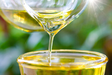 Pouring olive oil in the a glass bowl at stone kitchen and inside green garden view. Prepare for cooking concept. Healthcare and Beauty Concept.
