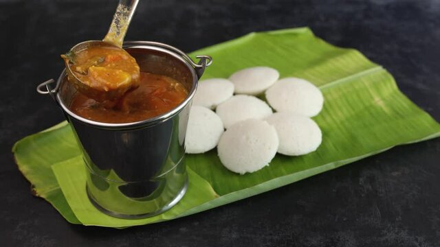 Many Idli idly sambar coconut chutney , tomato chutney serving breakfast vegetarian food South Indian restaurant Kerala Tamil Nadu India Sri Lanka banana leaf 4K slow motion video. steamed rice cakes 