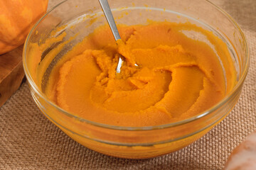 Pumpkin puree in a glass bowl close up on kitchen table