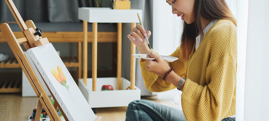 Cropped shot of female artist painting on canvas at home. Hobby and leisure concept.