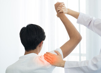 Female physiotherapists provide physical assistance to male patients with shoulder injuries massage their shoulders for muscle recovery in the rehabilitation center. Physiotherapy concepts