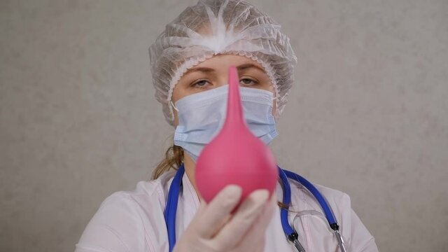 Close-up portrait of a doctor or nurse in a medical uniform with an enema in her hands in a hospital.