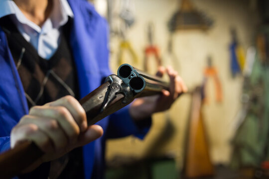 Close-up of break-action of horizontal double-barreled hunting shotgun in hands of gunsmith in workshop.