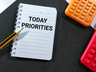 Selective focus.Word TODAY PRIORITIES on notebook with pencil and calculator on black...