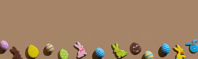 Easter banner. Festive ornament. Spring holiday decoration. Greeting card. Colorful gingerbread cookie bunny painted eggs creative composition in row isolated on beige brown empty space background.