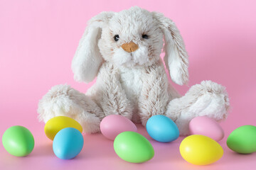 Easter bunny with colored eggs on pink background