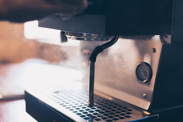 Barista heats milk steam for making lattes at coffee shop.