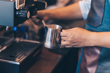 Barista heats milk steam for making lattes at coffee shop.
