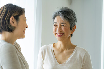 笑顔で会話する30代日本人女性とシニア女性