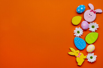 Easter background. Holiday ornament. Festive homemade food decor. Gift card. Bright gingerbread bunny cookie color egg flower creative arrangement isolated on orange empty space.