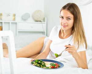 Obraz na płótnie Canvas Portrait of lady eating vegetable salad in bed at home alone. High quality photo