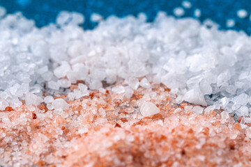 Pink coarse salt crystals on a blue table. Himalaya salt. Background for advertising salty.