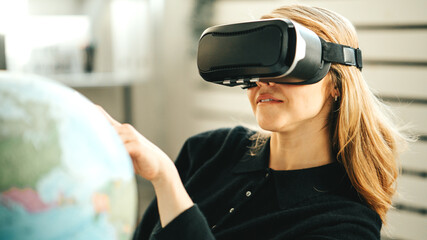 Pretty woman using vr headset and world map dreaming of travel to any destination while global lockdown