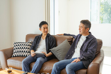 ソファに座りくつろぐ日本人シニア男性と息子