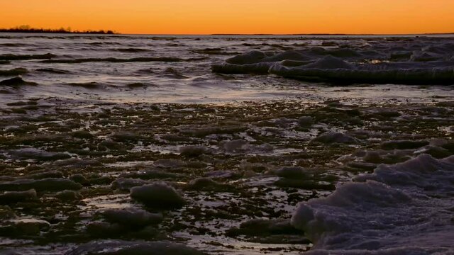 Closeup of floating ice pushed against a shoreline of brash ice after sunset.