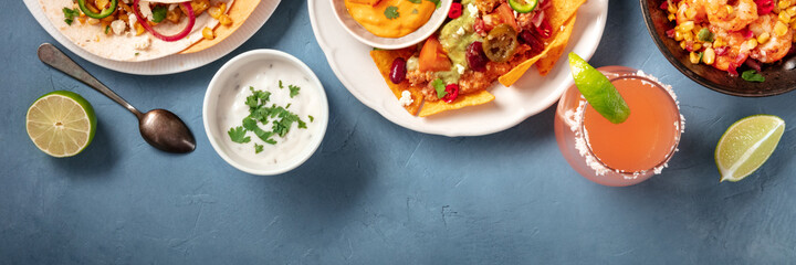 Mexican food panoramic banner with a place for text. Nachos, tacos, dips and cocktails on a blue background