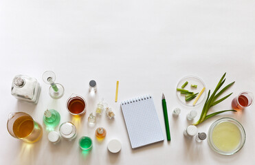 Laboratory glassware with chemicals and solutions on a white laboratory table next to green fresh aloe vera plants. Development of natural cosmetics with organic extracts for health and body care