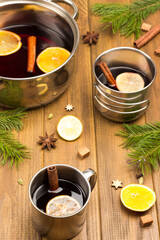 Citrus mulled wine with spices in metal mugs and saucepan