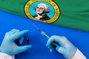 Washington Vaccination. Hands of doctor holding syringe and coronavirus (COVID-19) vial vaccine on flag Washington