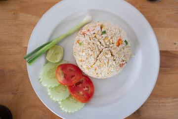 Thai fried rice with egg and pork served with vegetable on the side.