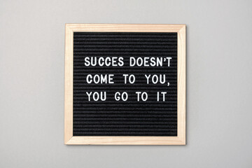 Success doesn't come to you, you go to it. Motivational quote on black letter board on gray background. Concept inspirational quote of the day. Greeting card, postcard