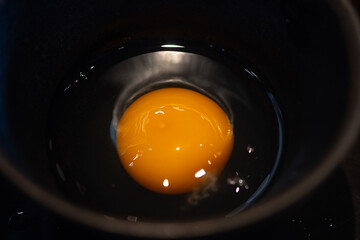 A raw egg in in small black bowl