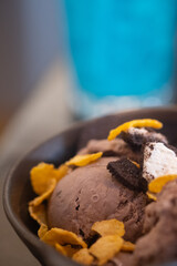 A bowl chocolate ice-cream scoops of various topping