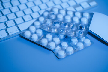 Keyboard and blister pills on blue background. Work and health concept