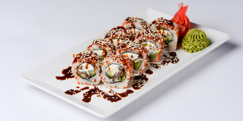Japanese sushi set with eel and unagi sauce. Cream cheese inside. Served on a white plate.