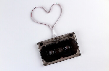 Old black audio cassette on a white background with a film heart. Cassette tape heart