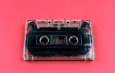 Old audio cassette on a red background. Audio recording accessory