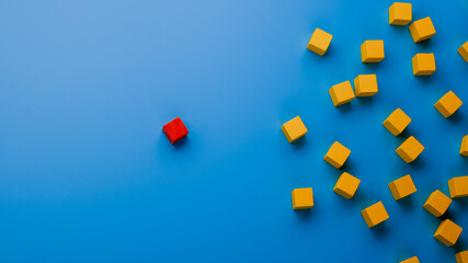 Red wooden block standing out from the crowd on blue background. Leadership and influence concept