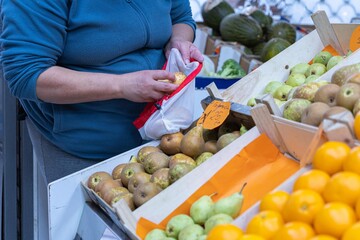Hands of a woman buying fruit in a greengrocer's shop