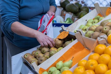 Hands of a woman buying fruit in a greengrocer's shop