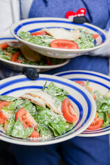 Caesar Salad served by waiter in restaurant or diner. Four plates of salad for healthy and full dinner.