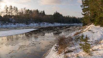 landscape with river in winter, tree-lined river bank, ice on the river, winter day
