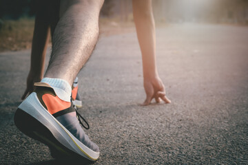 Athlete man in running start pose on the road. Mans fitness with the sun effect in the background and open space around him