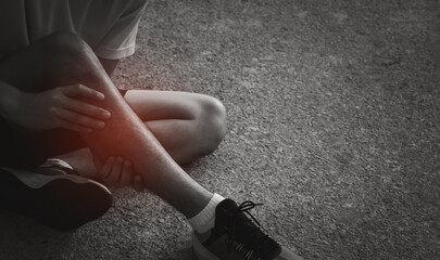 leg pain, man sit on the floor holding sore and painful muscle during a running workout, black and white monotone with red pink bright place. Person injured when exercising or running.