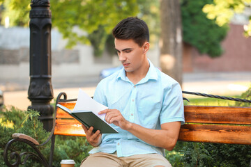 Obraz premium Young man reading book in park