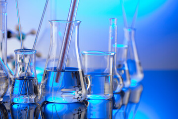 Laboratory concept background. Glass tubes and beakers on blue background.