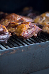 Smoke rising around a slow cooked beef brisket on the grill grates of a smoker barbecue. Grilled spare ribs macro - pork ribs