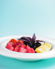 A plate with black homemade pasta with salted salmon, served on a blue background table.