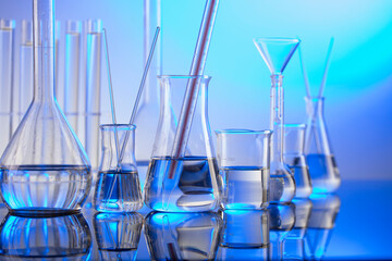 Laboratory concept background. Glass tubes and beakers on blue background.