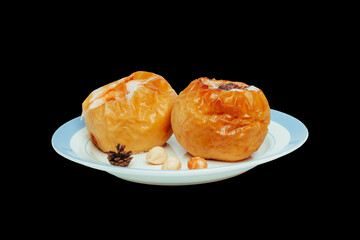 baked apples on a plate isolated on black. Fruit dessert stuffed with walnuts, pine nuts, honey and cinnamon