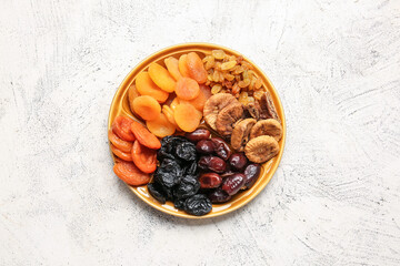 Plate with different dried fruits on light background