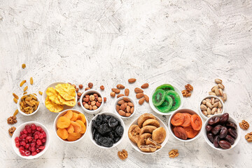 Fototapeta na wymiar Bowls with different dried fruits and nuts on light background