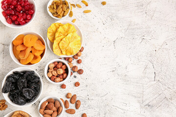 Bowls with different dried fruits and nuts on light background