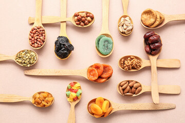 Spoons with different dried fruits and nuts on color background