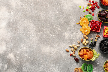 Bowls with different dried fruits and nuts on gray background