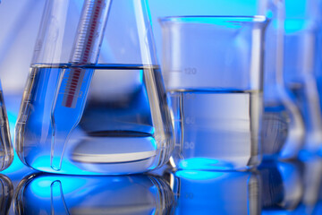Laboratory concept background. Glass tubes and beakers on blue background.